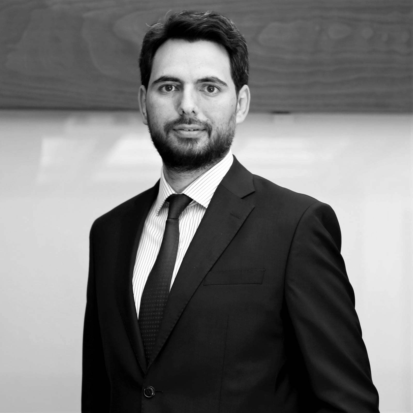 Hamdi Uğur in a suit and tie in an office; black-and-white portrait